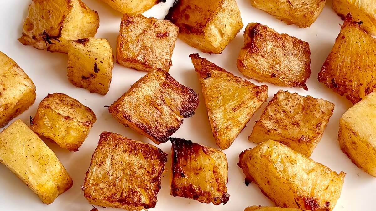 Pieces of baked pineapple on a white plate.