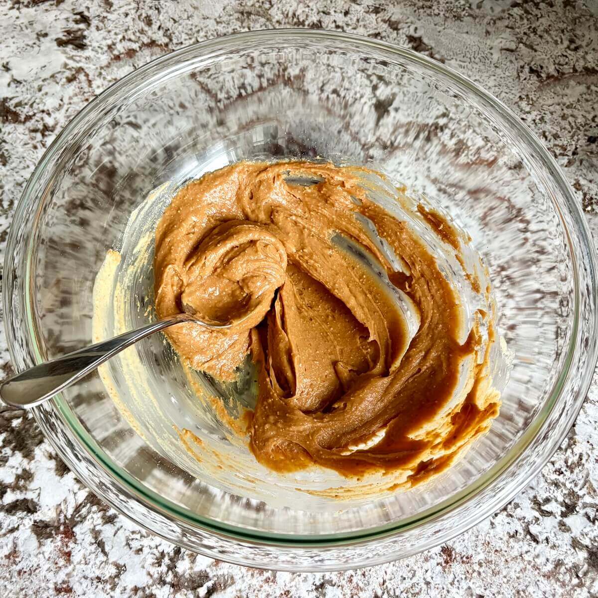 Peanut butter brownie batter ingredients in a glass mixing bowl.