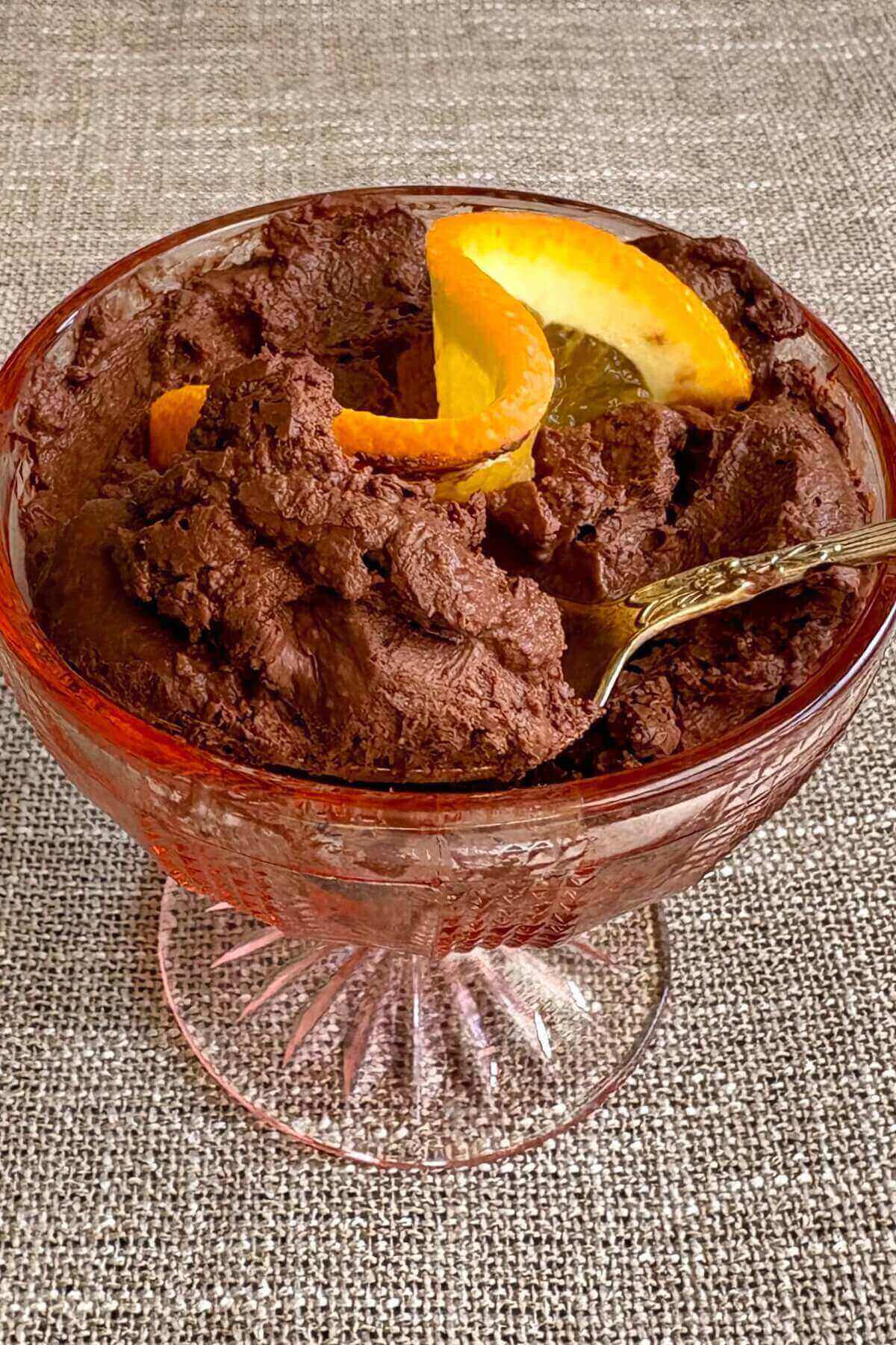 Chocolate mousse with an orange twist on top in a glass dish.