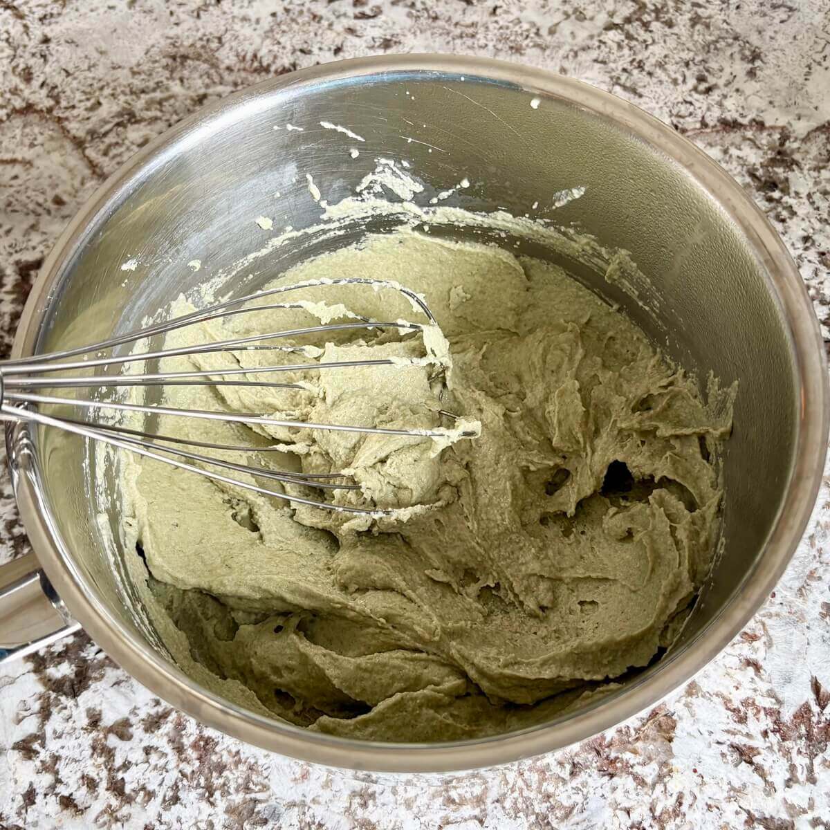 Creamy vegan cheese made with pumpkin seeds in a steel pot with a whisk.