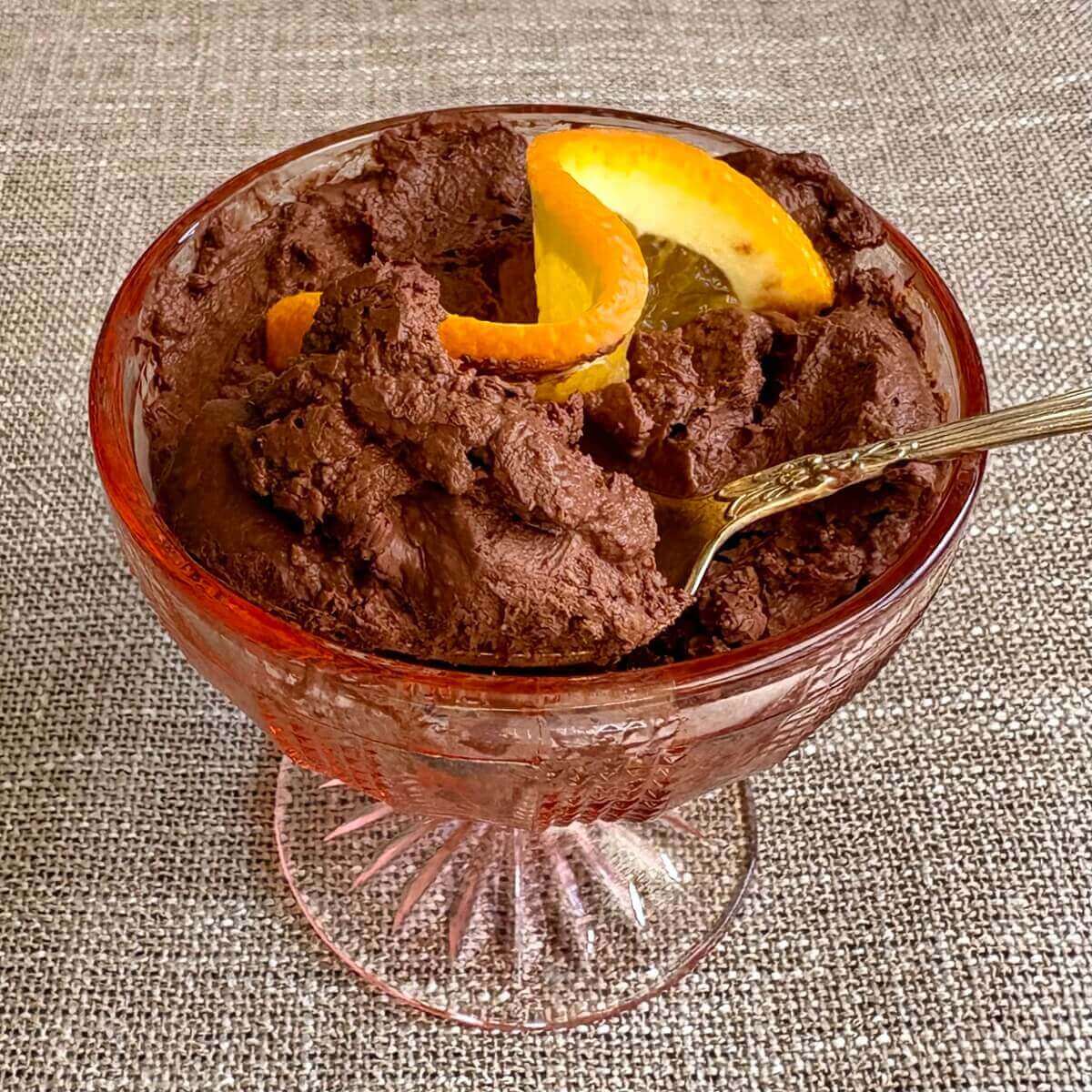 Dark chocolate orange mousse in a glass dish with an antique silver spoon.