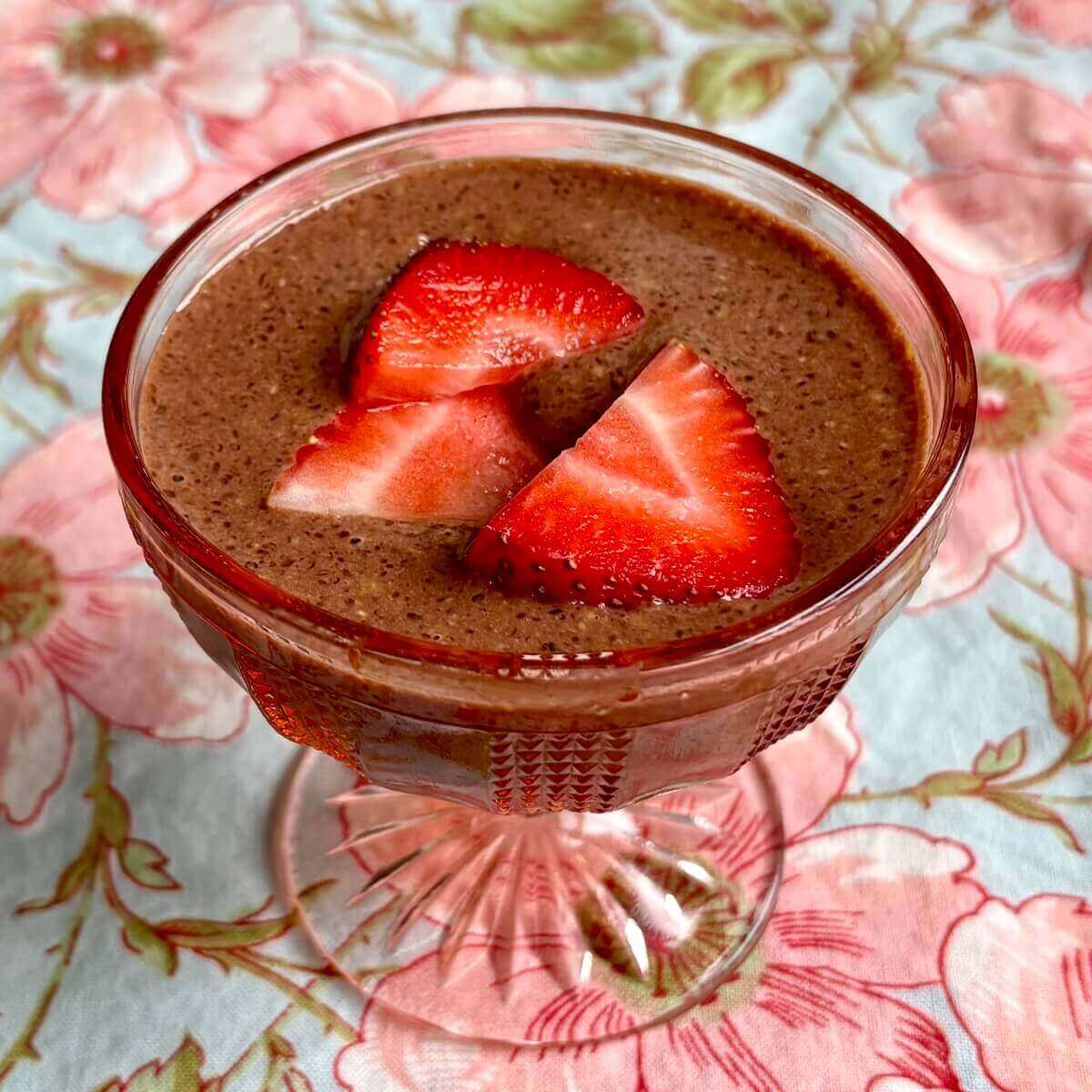 Flaxseed pudding topped with strawberry slices in a vintage dish.