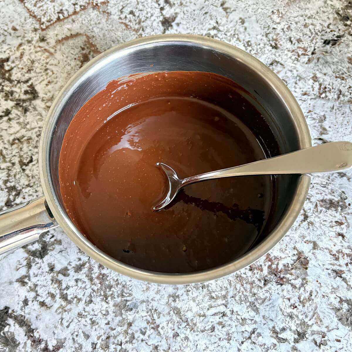 Melted chocolate, peanut butter, and other ingredients for frosting in a steel pot.