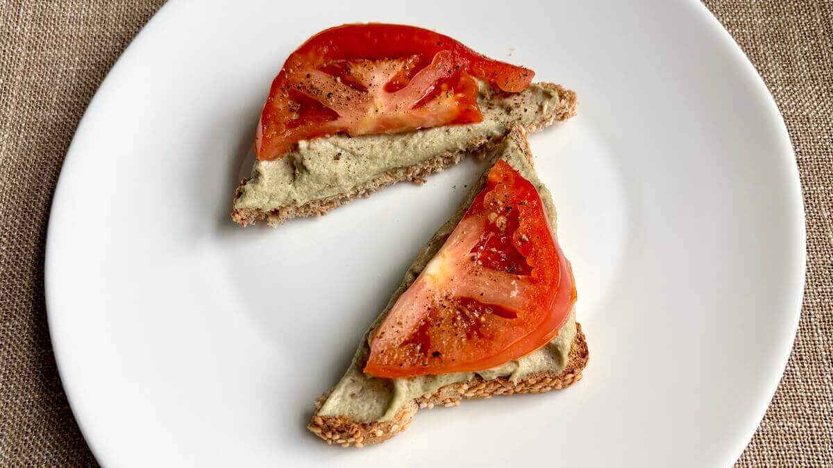 Toast spread with vegan cheese on a white plate.
