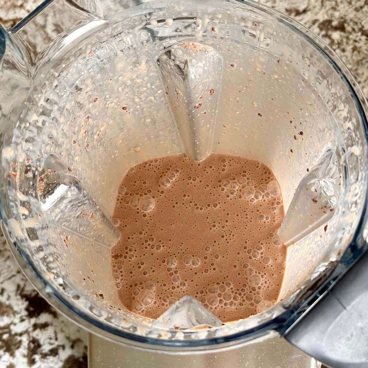 Cashew butter and other ingredients for a smoothie blended in a blender.