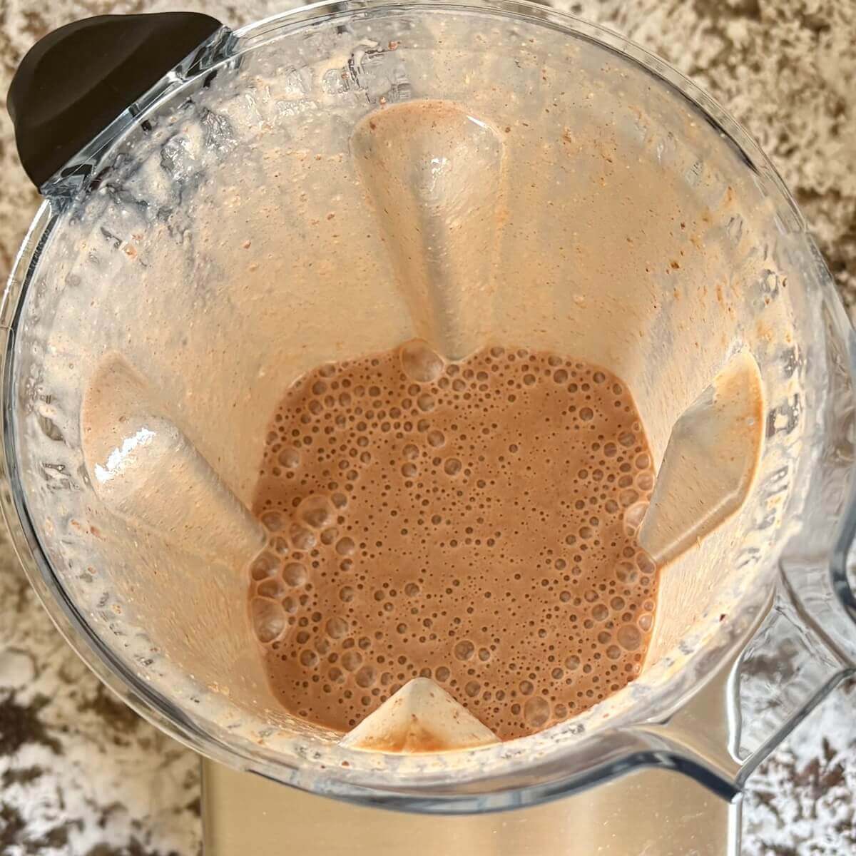 Flaxseed and other ingredients for a smoothie blended in a blender.