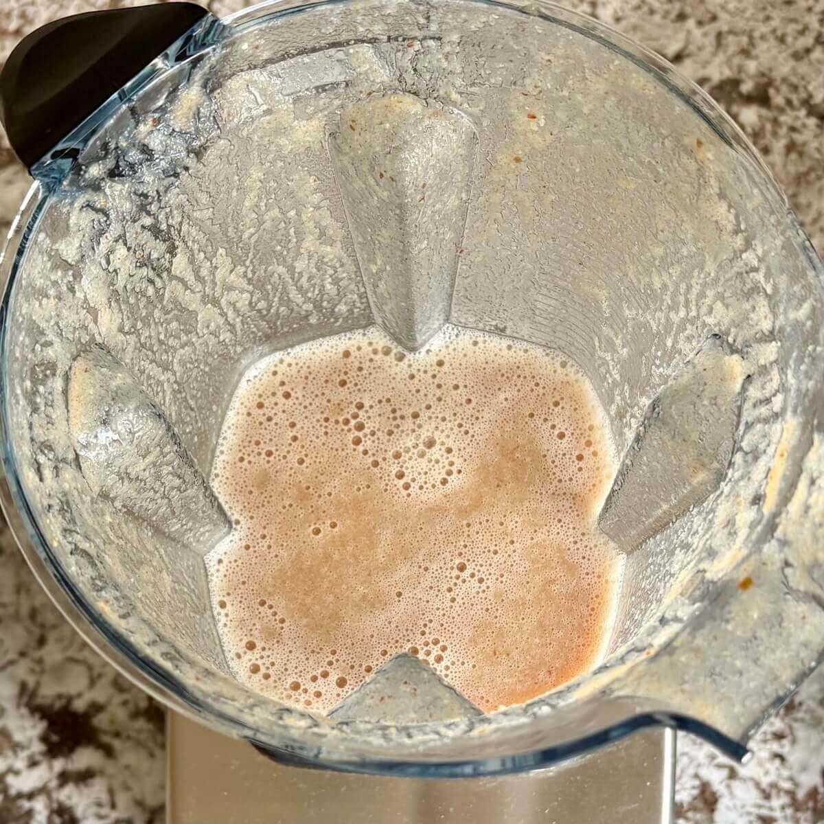 A whole lemon and other ingredients for a smoothie blended in a blender.