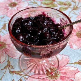 Blueberry compote (no sugar added) in a glass dish with an antique spoon.