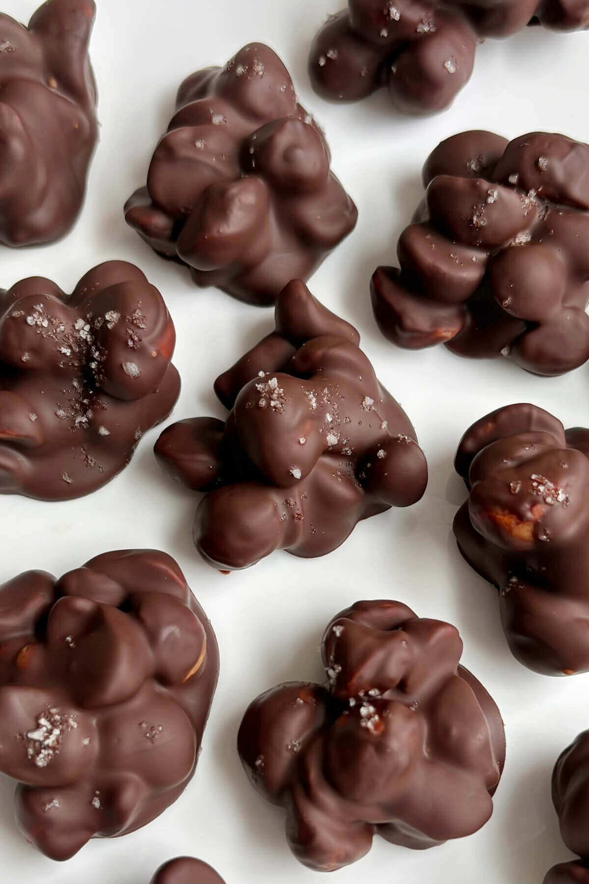 Chocolate macadamia clusters sprinkled with sea salt on a plate.