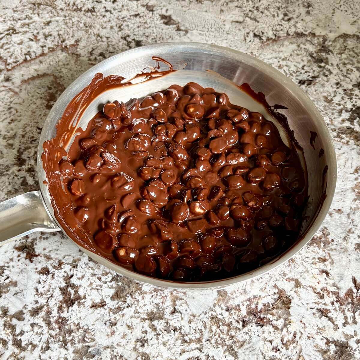 Chocolate coated macadamia nuts in a steel pan.