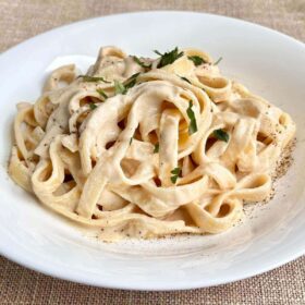 Noodles smothered in a creamy cashew pasta sauce in a bowl.