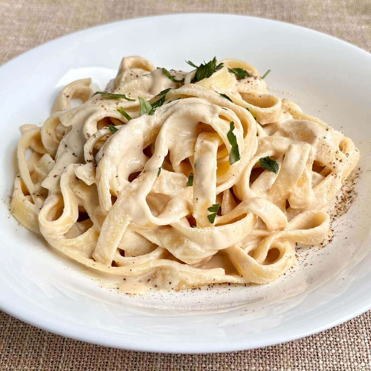 Noodles smothered in a creamy cashew pasta sauce in a bowl.