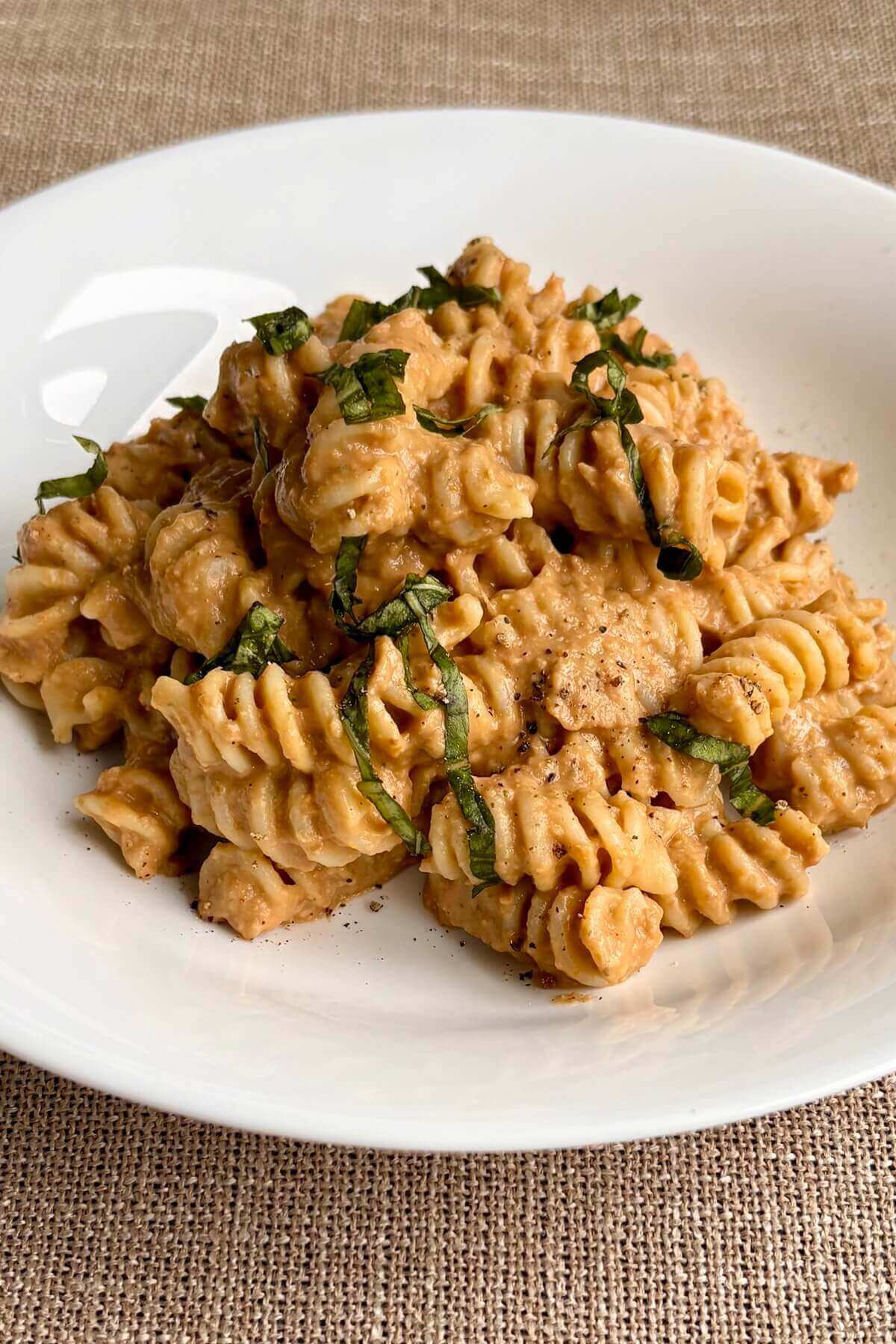 Noodles with lentil sauce garnished with fresh basil.