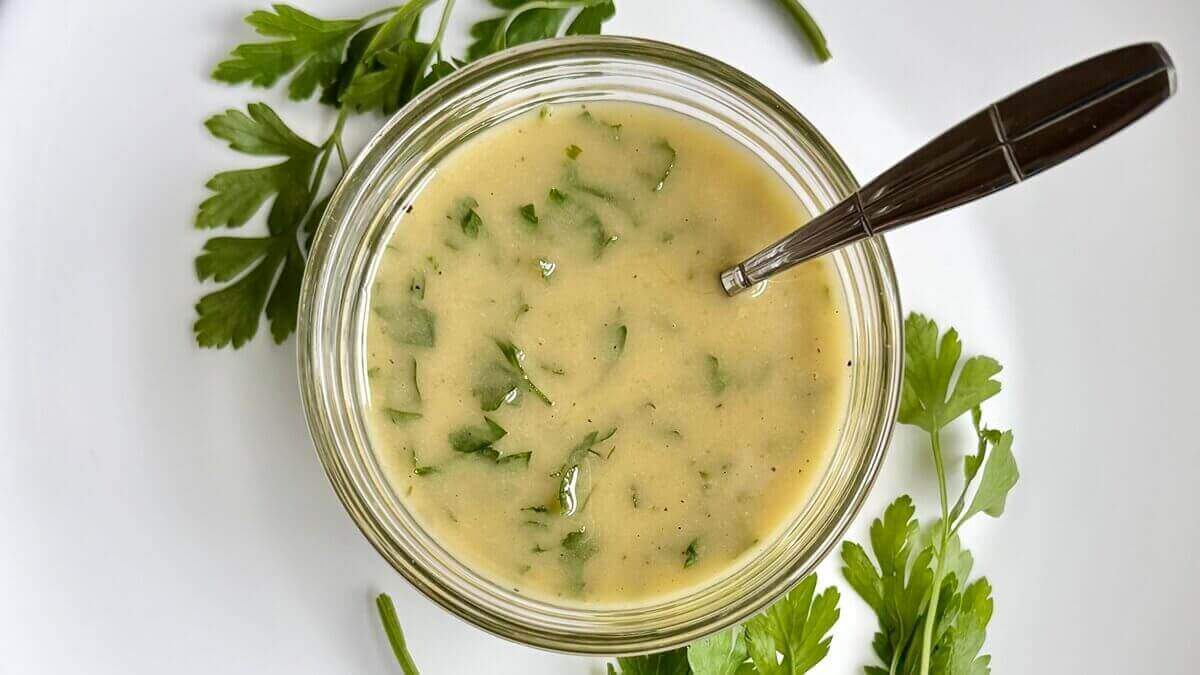 Parsley vinaigrette in a glass bowl with a spoon.
