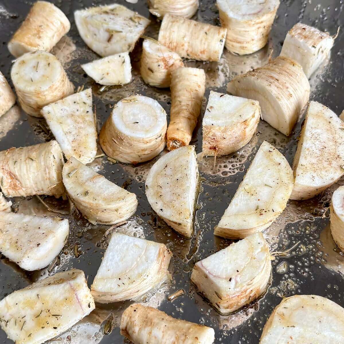 Pieces of raw parsley root on a sheet pan.