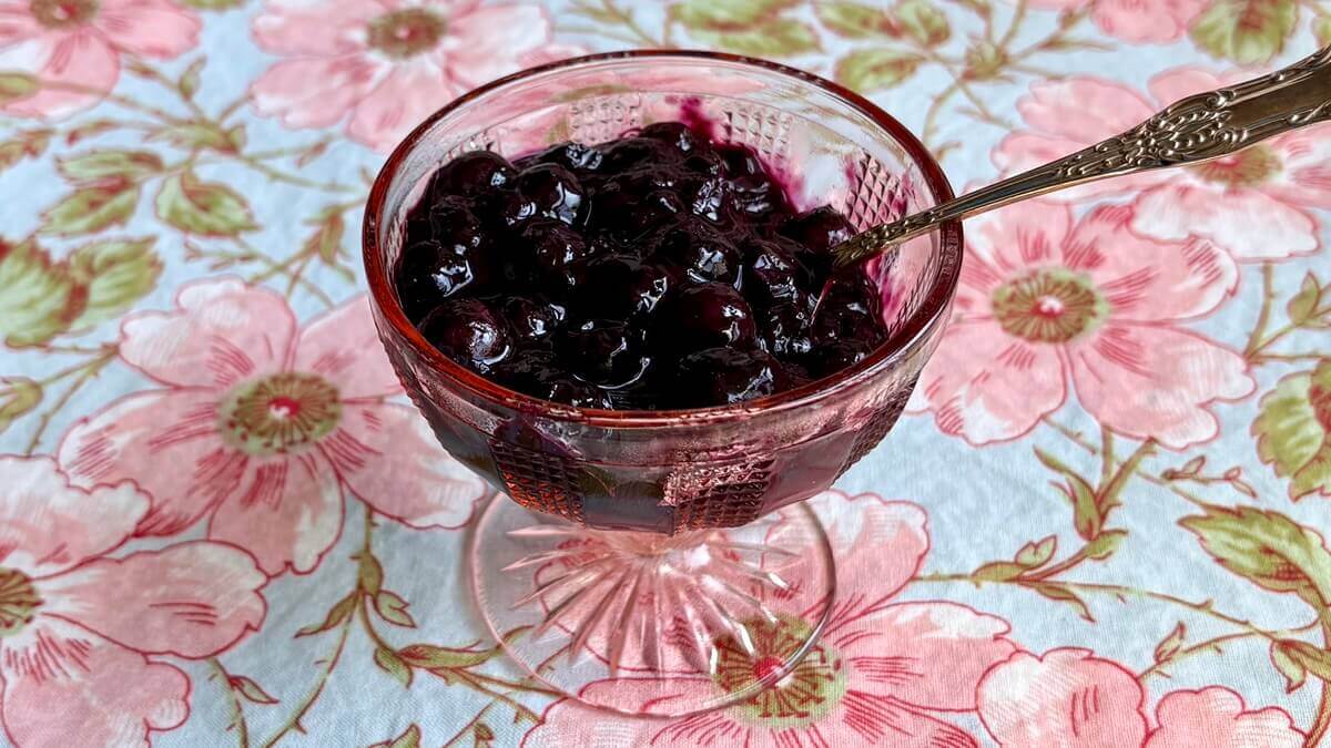 Refined sugar-free blueberry compote in a glass dish with a spoon.