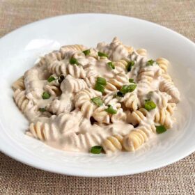 Noodles with a creamy vegan walnut sauce in a white bowl.