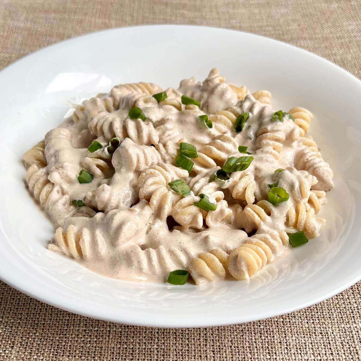 Noodles with a creamy vegan walnut sauce in a white bowl.