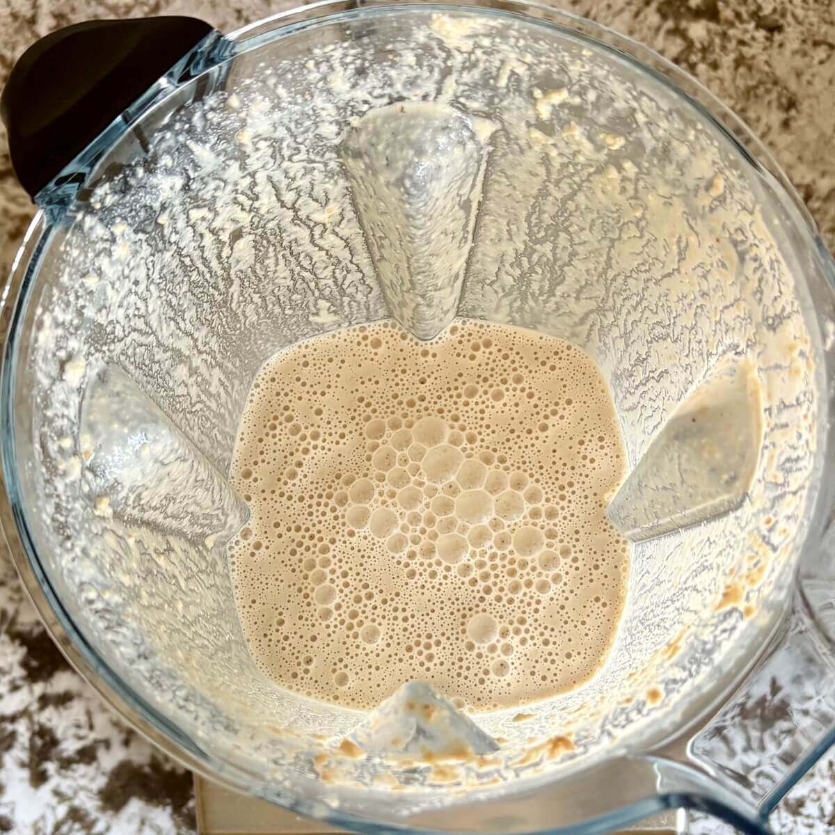 Blended cashews and other ingredients for mousse in a blender.