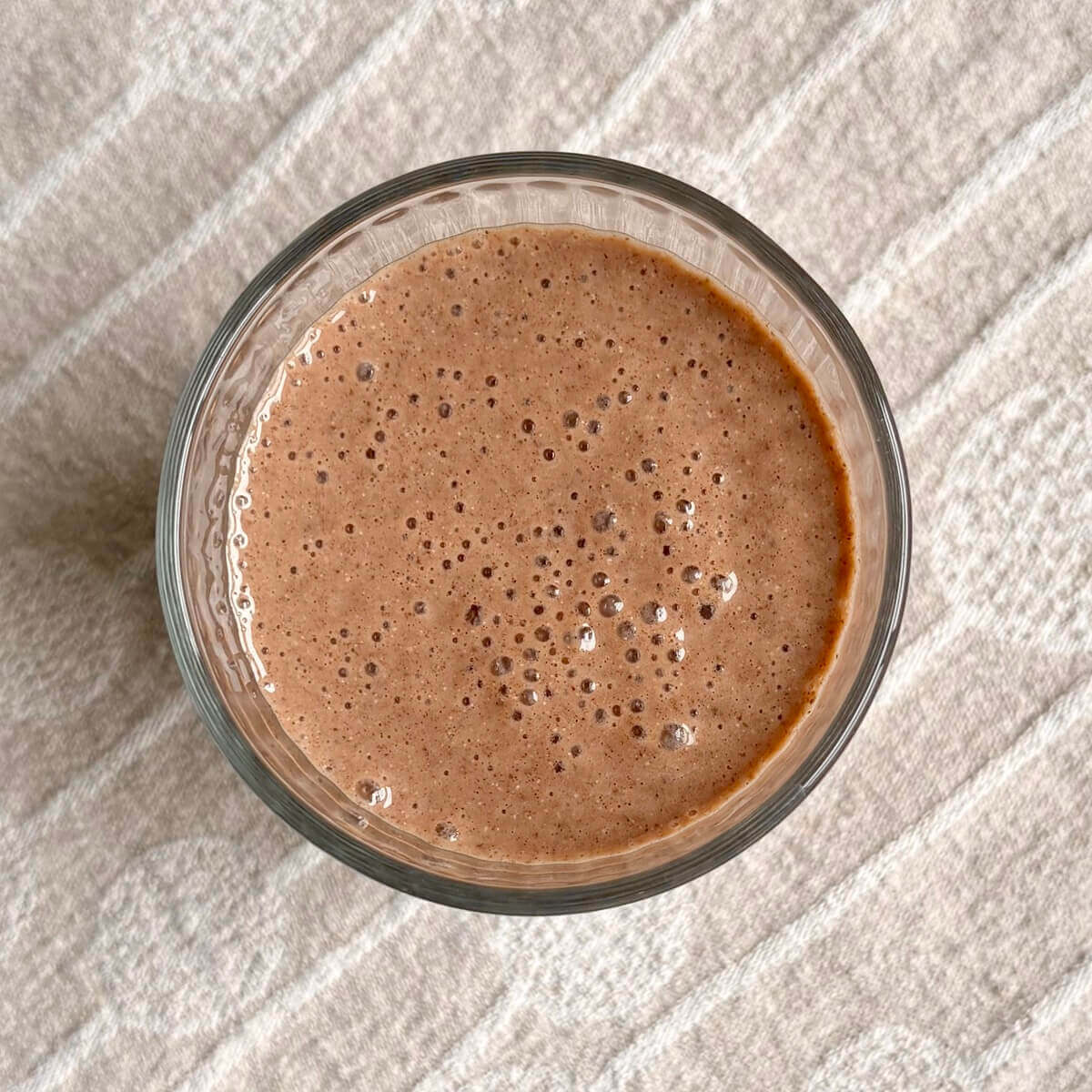 A chocolate chia smoothie on a beige placemat.
