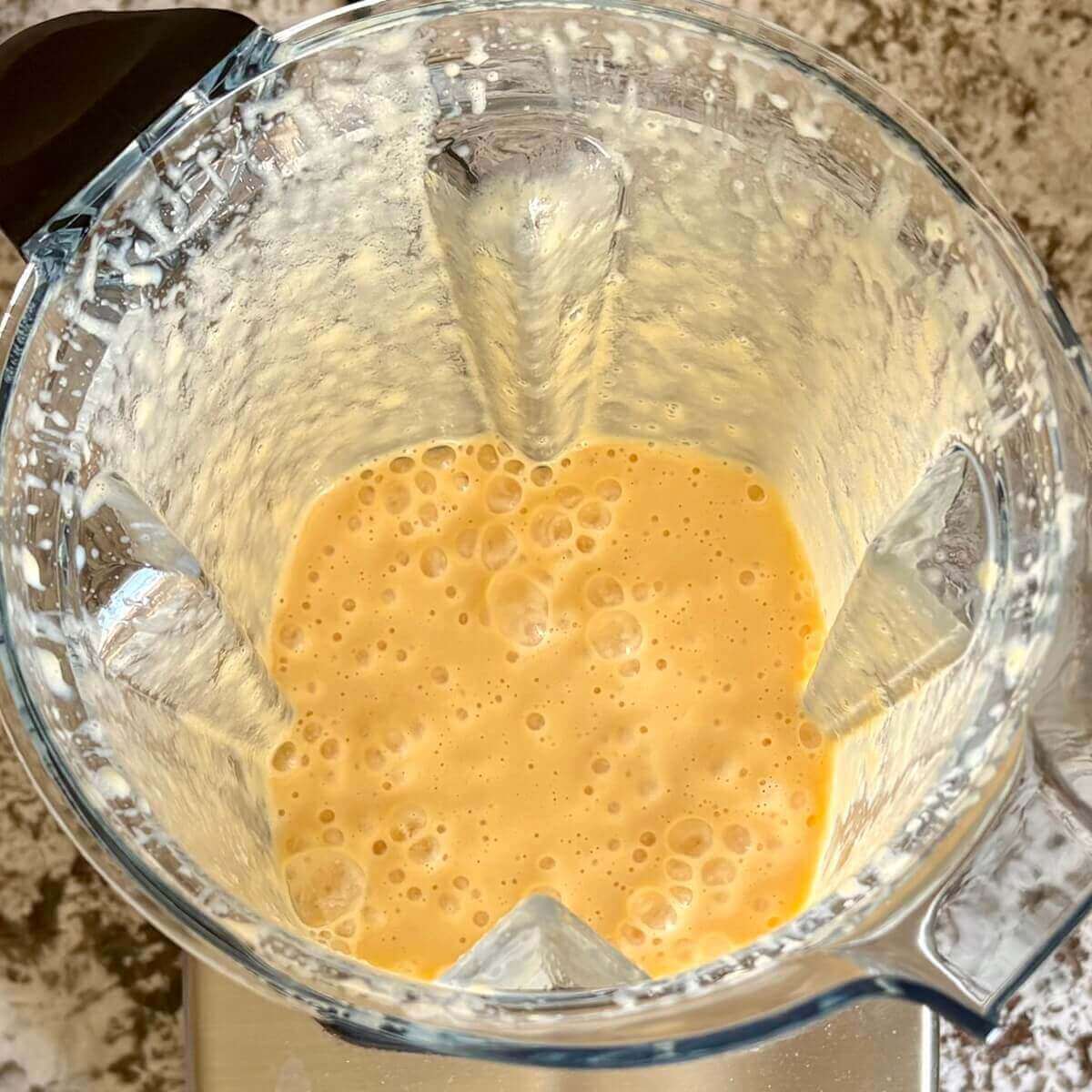 Mango and other ingredients for a creamy smoothie blended in a blender.