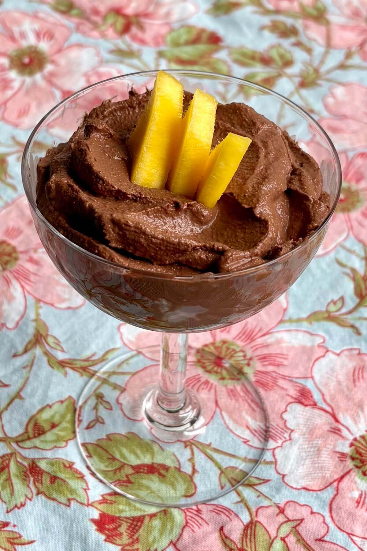 Mango dark chocolate mousse in a dish garnished with mango slices.