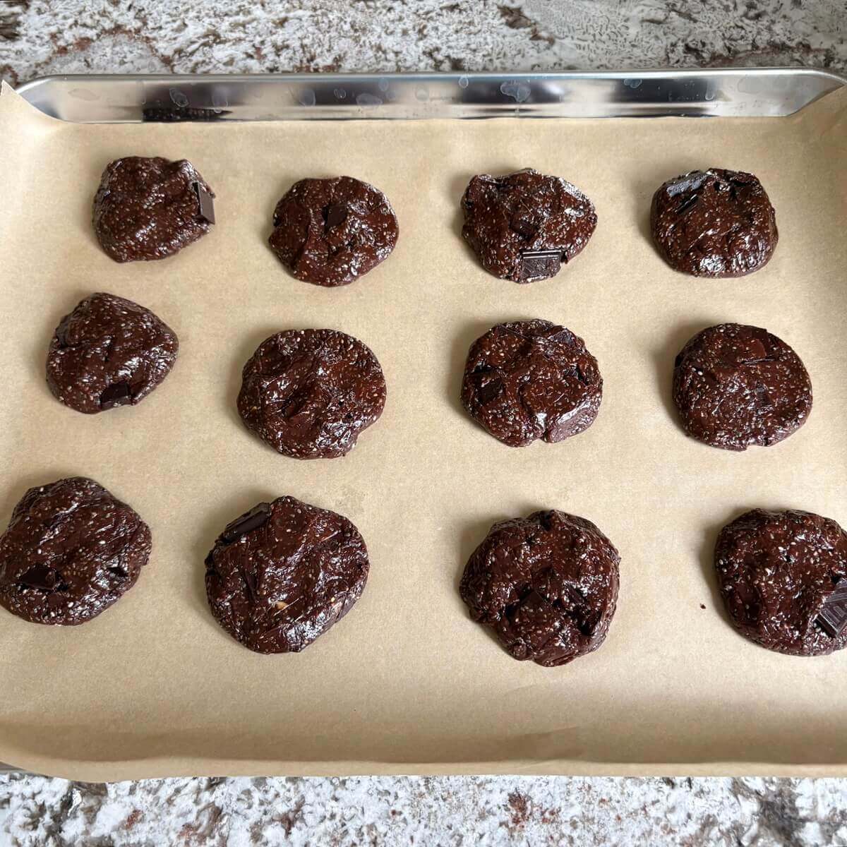 Raw chia cookies on a baking sheet lined with parchment paper.