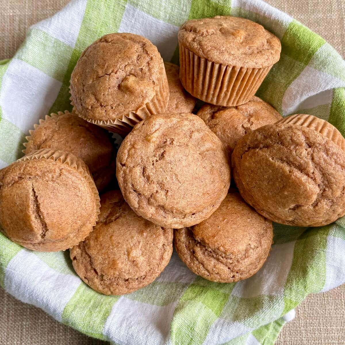 Vegan pear muffins in a basket lined with a green gingham towel.