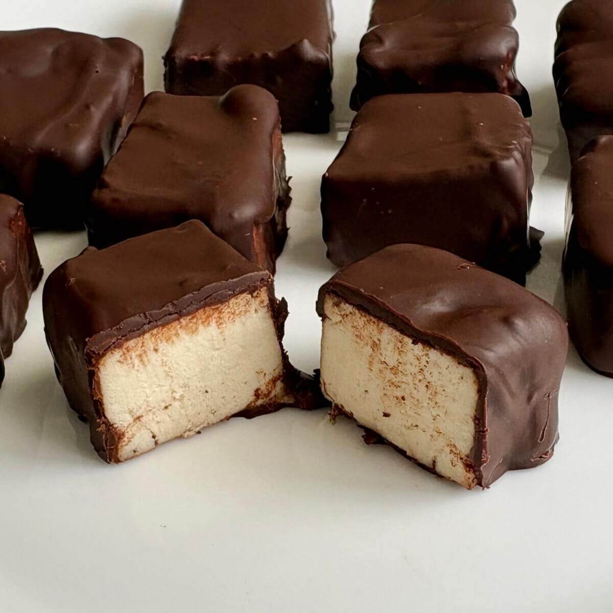 Chocolate covered tofu pieces on a white plate.
