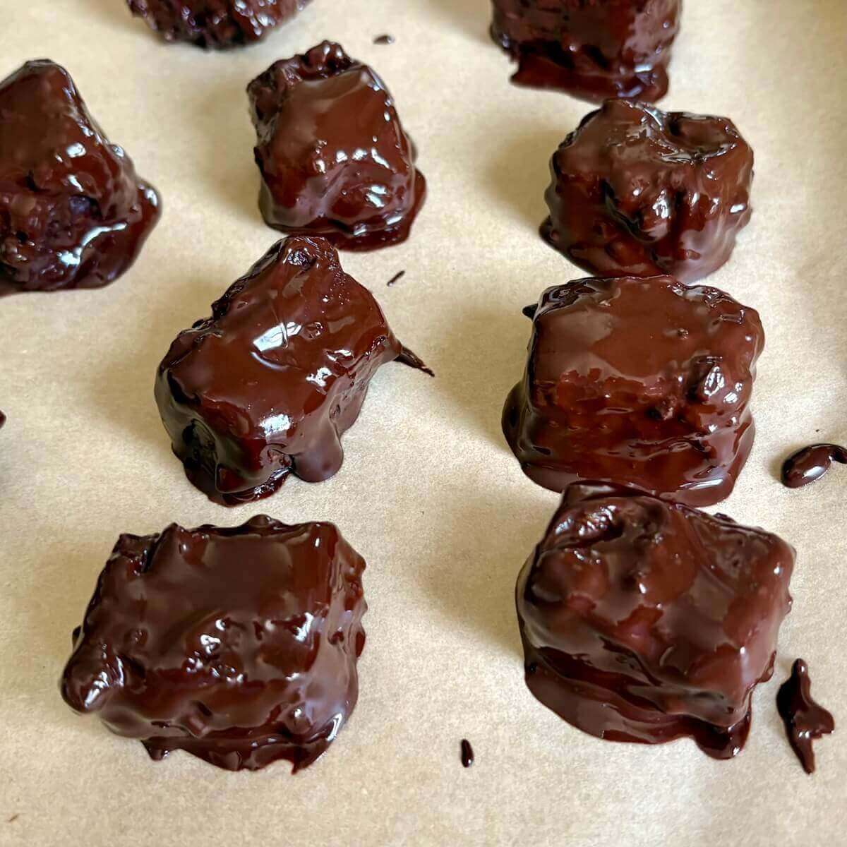 Chocolate-dipped tempeh pieces on a sheet pan lined with parchment paper.