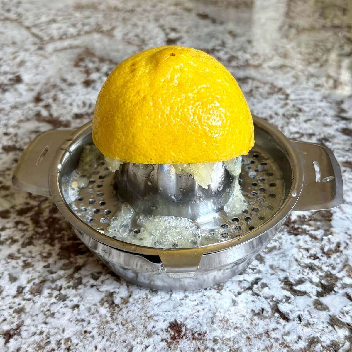 Half a lemon being juiced in a citrus juicer.