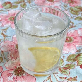 A glass of monk fruit lemonade with ice cubes and a lemon slice.