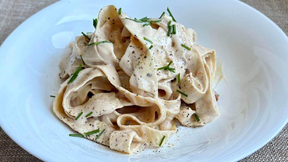 Tofu skin pasta in a bowl with chives sprinkled on top.