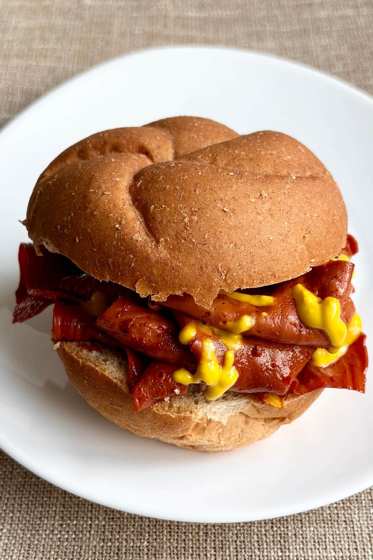 A vegan beef sandwich on a white plate.