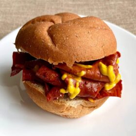 A vegan roast beef sandwich drizzled with mustard.