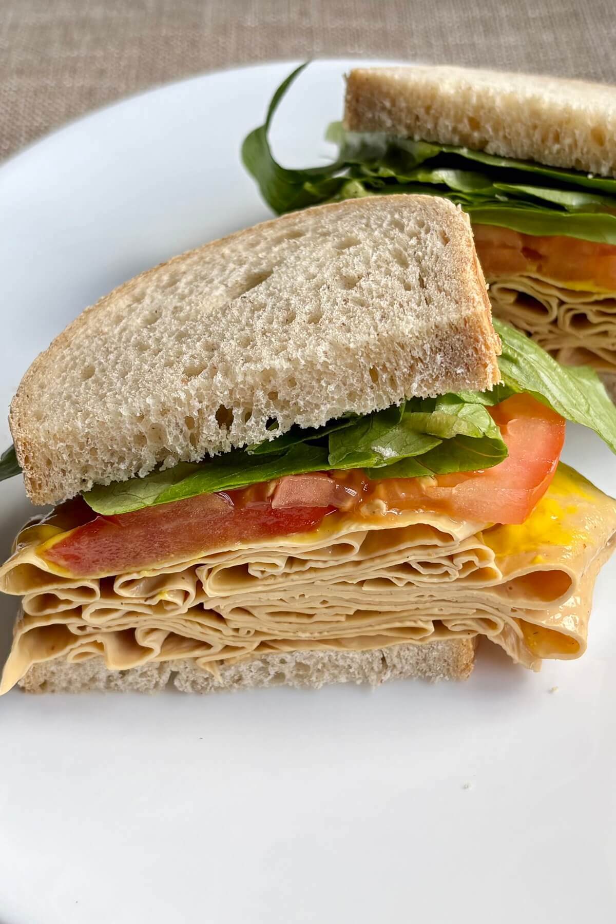A vegan turkey deli sandwich on a white plate.
