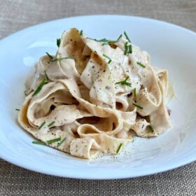 Yuba noodles smothered in a creamy sauce in a white bowl.