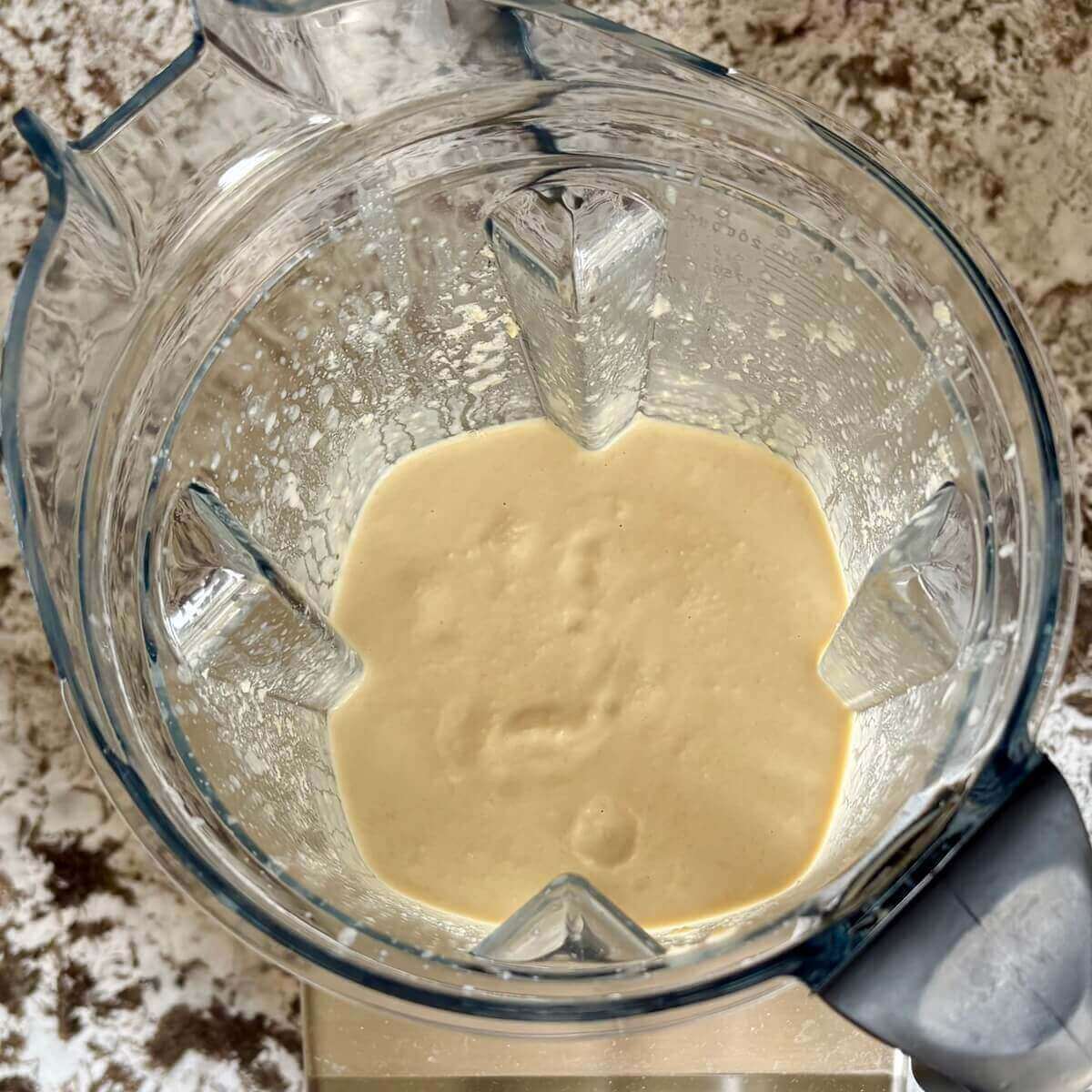 Blended tempeh and other ingredients for vegan cheese in a blender.