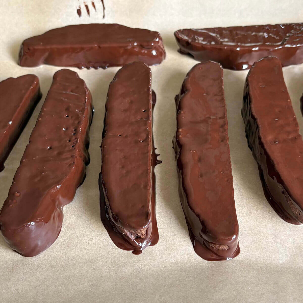 Chocolate dipped seitan slices on a sheet pan lined with parchment paper.