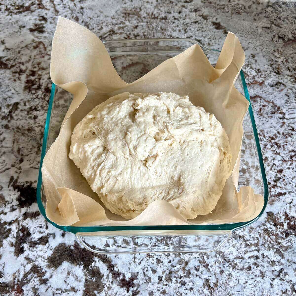 A dough made with tofu in a baking dish lined with parchment paper.