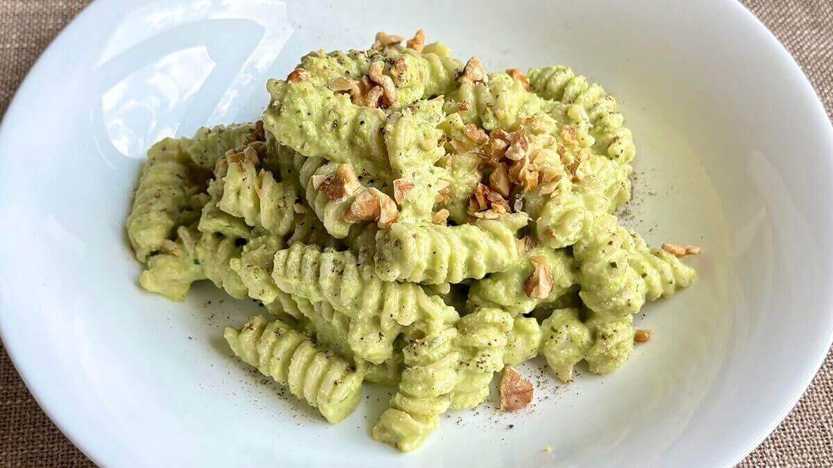 Pasta tossed with edamame sauce and garnished with chopped walnuts.