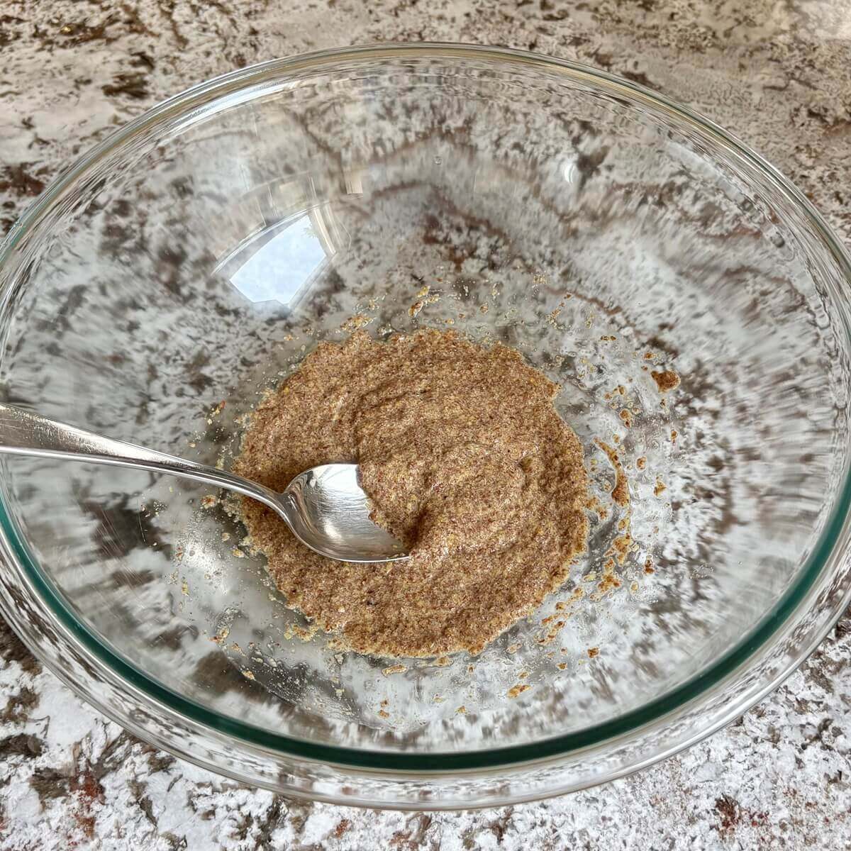 Ground flaxseed and water gelling in a glass mixing bowl.
