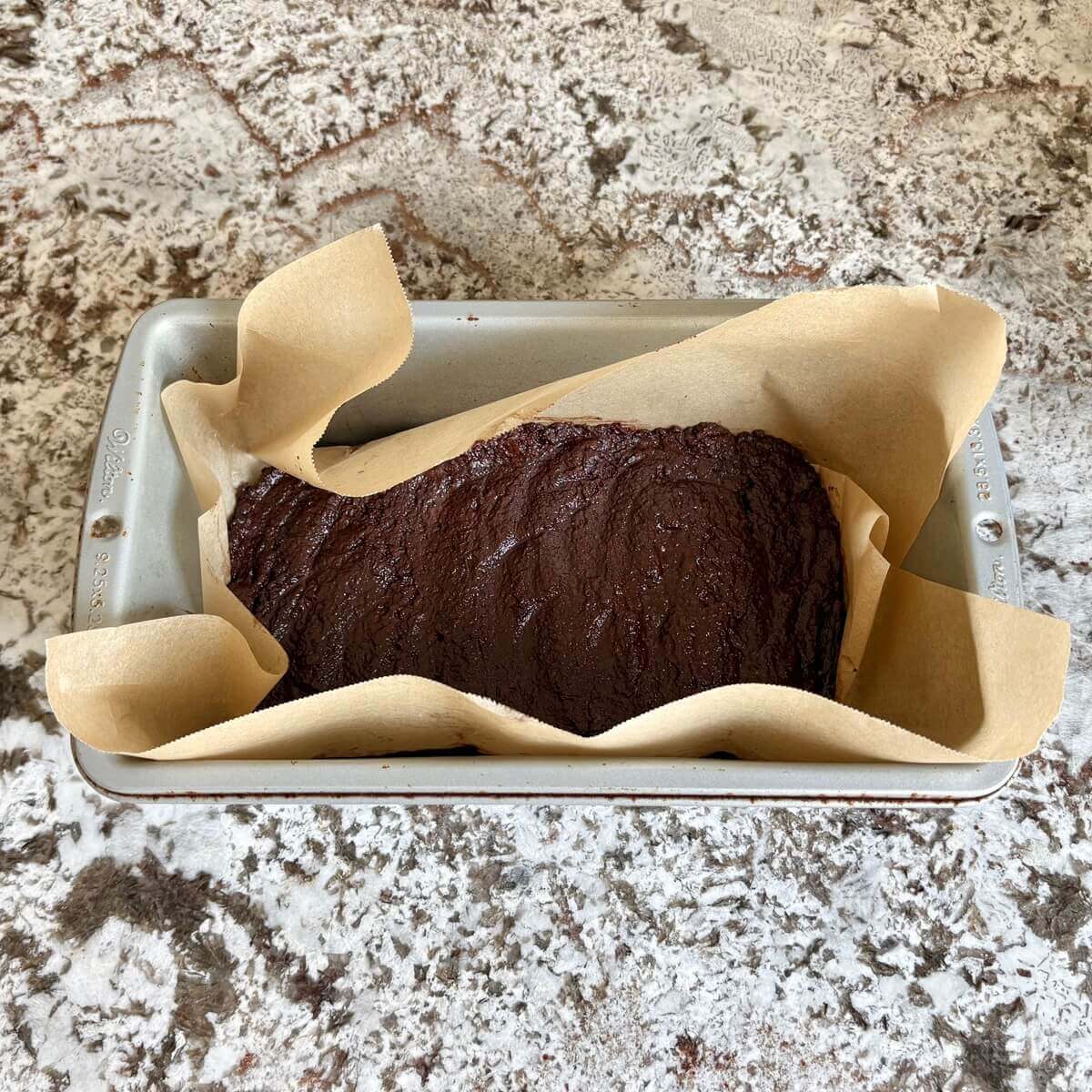 Chocolate flaxseed treat batter in a loaf pan lined with parchment paper.