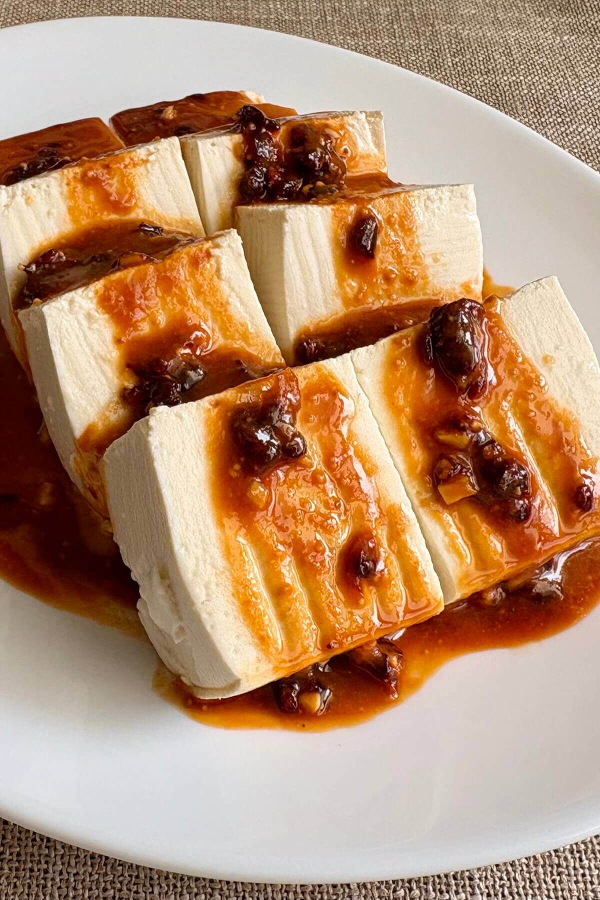Slices of saucy no-cook tofu on a white plate.