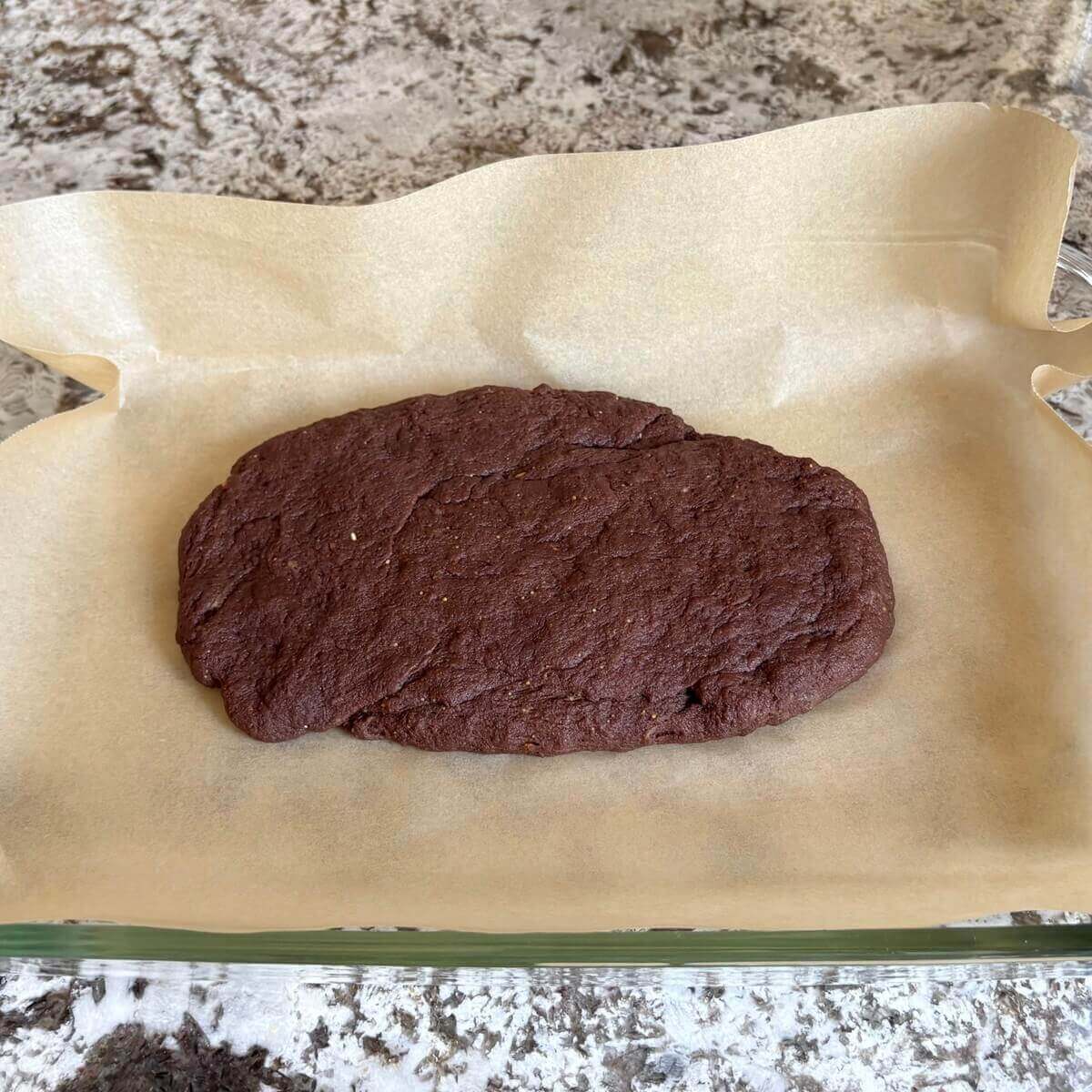 Seitan dessert dough in a baking dish lined with parchment paper.