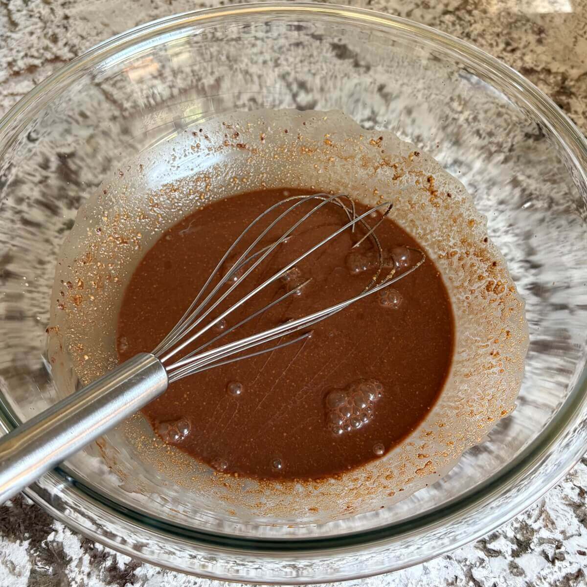 Wet ingredients for sweet seitan in a mixing bowl with a whisk.