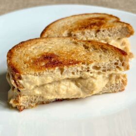 A sandwich oozing with tempeh cheese.