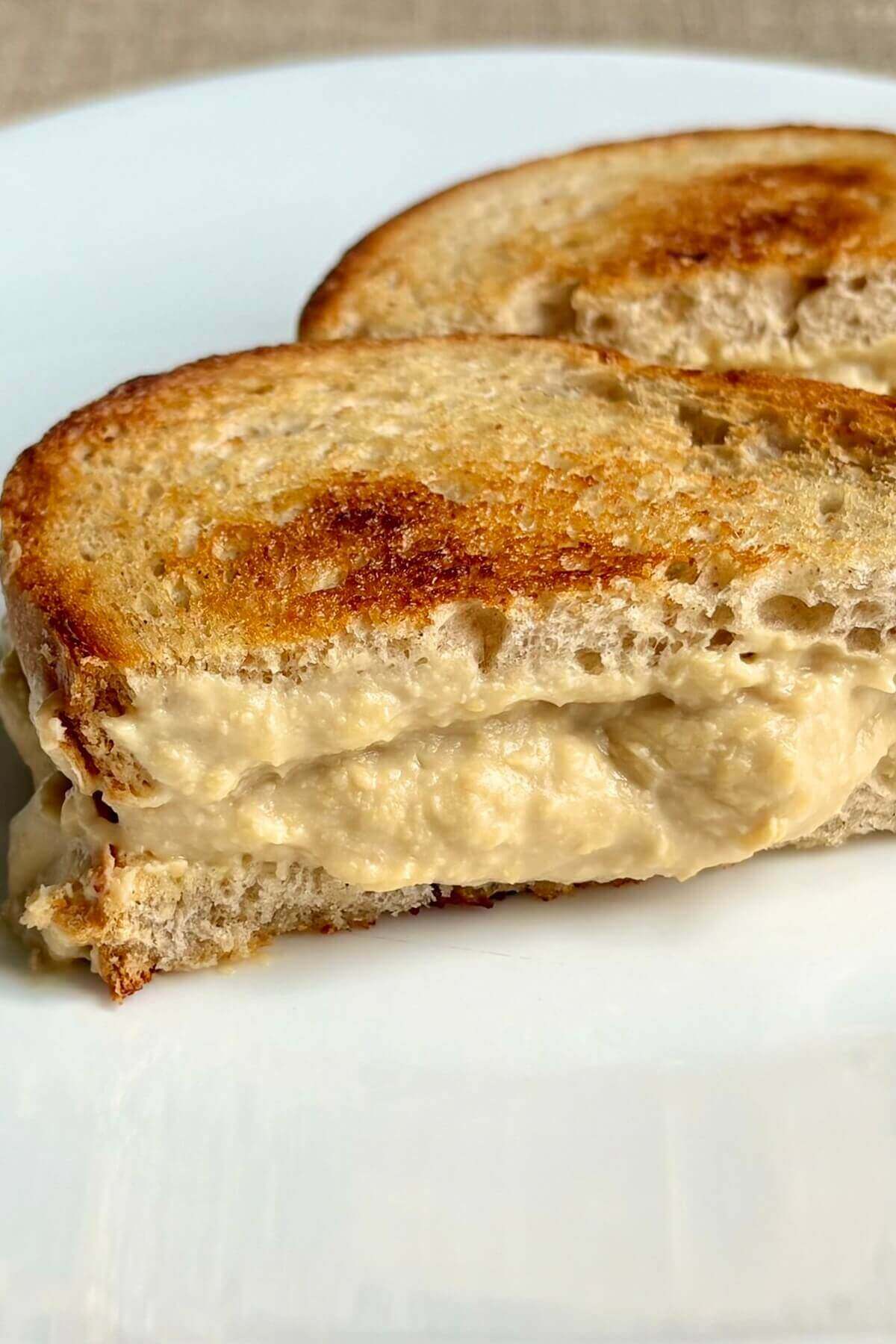 A tempeh vegan grilled cheese sandwich on a white plate.