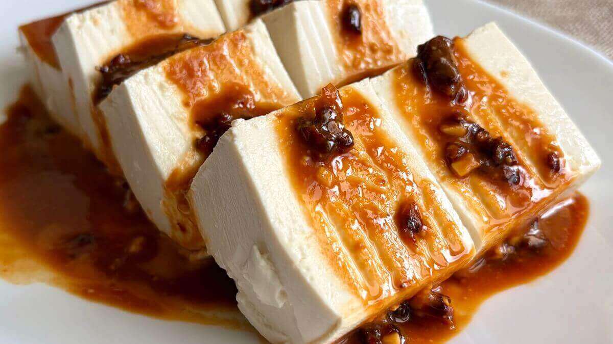 Slices of tofu drizzled in sauce on a plate.