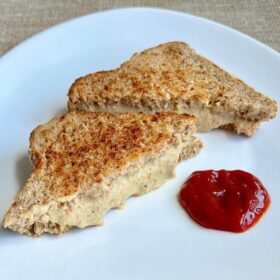 A grilled chia seed cheese sandwich on a white plate with ketchup.
